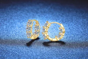 Détail macro de boucles d'oreilles créoles en or moissanite 4 carats sur fond bleu