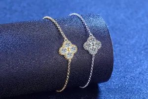 Macro shot of silver and gold clover bracelets with diamonds on blue display