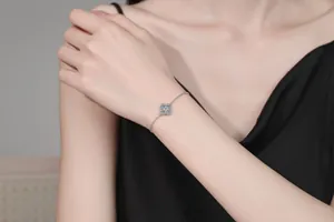 Macro detail of 925 silver four-leaf clover bracelet with sparkling moissanite on wrist