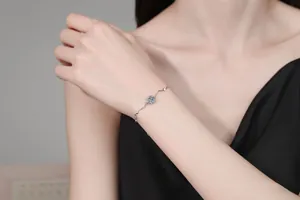 Detail of S925 sterling silver bracelet featuring a flower charm and wave link design