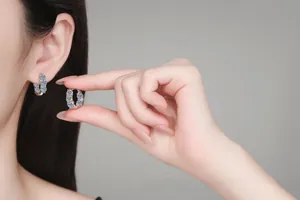 Détail de boucles d'oreilles créoles en argent 925 avec moissanite bleue sur modèle