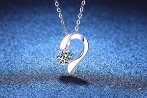 Gros plan d'un pendentif cœur en argent serti d'une pierre moissanite sur fond bleu