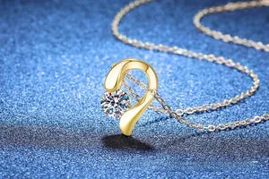 Macro d'un pendentif en or avec pierre moissanite sur fond bleu foncé étincelant