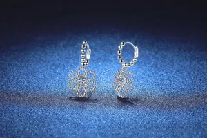 Macro view of S925 sterling silver camellia drop earrings with sparkling round moissanite