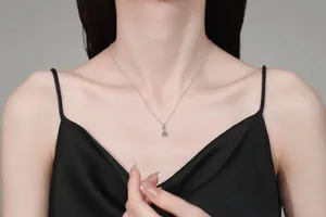 Close-up of S925 silver necklace with double blue moissanite pendant on a female model