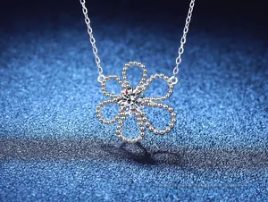 Macro shot of S925 silver flower pendant with sparkling D-color moissanite on blue background