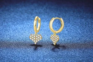 Detail of gold heart earrings featuring sparkling pavé crystals on a deep blue texture