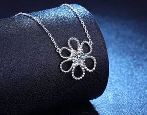 Macro shot of silver hollow camellia flower pendant with sparkling center stone