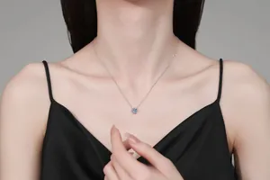 Close-up of 1 carat round blue moissanite pendant on silver chain worn by a model