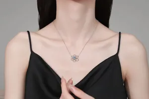 Detail of S925 silver flower necklace with blue gemstone on model collarbone