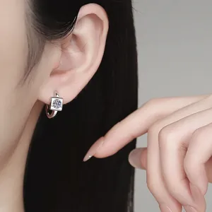 Square silver stud earrings with D color moissanite stones shown on ear model