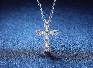 Macro shot of silver cross pendant with brilliant round-cut stones on blue texture
