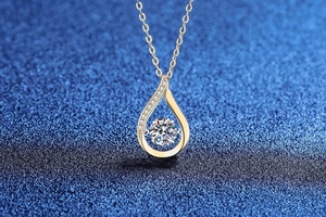 Macro detail of dancing moissanite pendant in water drop shape with gold finish