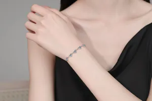 Macro detail of S925 silver bracelet featuring heart-shaped blue moissanite stones on wrist