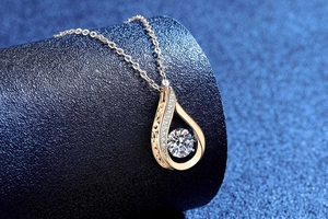 Detail of teardrop necklace pendant in gold finish with round brilliant moissanite stone