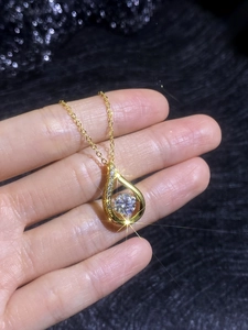Macro shot of gold teardrop pendant featuring a large round center moissanite stone