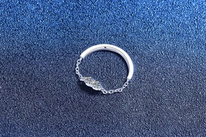 Detailed view of silver chain ring with double moissanite stones on navy background