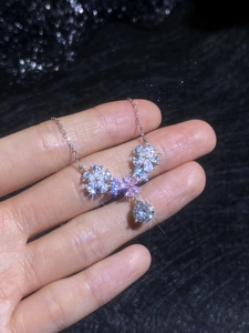 Close-up of 925 silver necklace with flower charms and pink moissanite stones