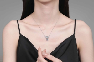 Close-up of S925 silver bow pendant with moissanite on a model in a black silk dress