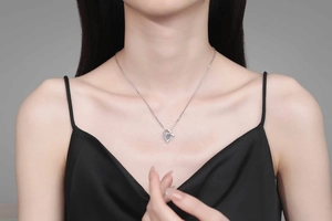 Close-up of S925 sterling silver heart pendant with blue gemstone on model's neckline