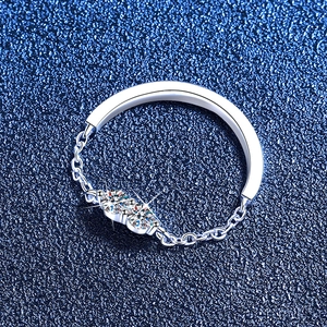 Minimalist chain ring with double moissanite stones in silver on a textured blue surface