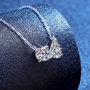 Elegant S925 silver necklace with round and pear-cut moissanite pendant on blue display