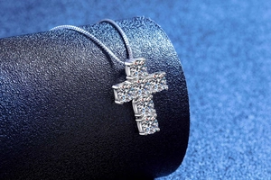 Macro del ciondolo a croce in moissanite da 3 carati su espositore in velluto blu
