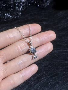 Macro shot of silver rose pendant with a sparkling moissanite stone on a delicate chain