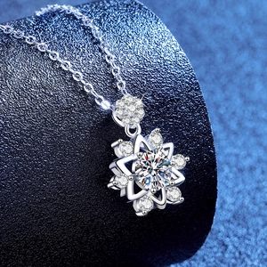 Sparkling moissanite snowflake necklace with starburst pendant on a deep blue background