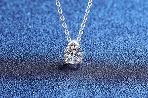 Macro view of brilliant round cut moissanite pendant with silver four-prong setting