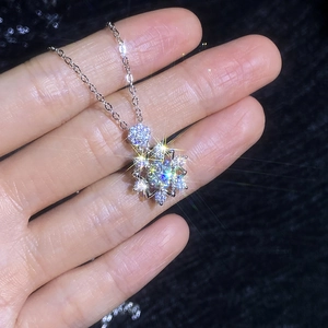 Hand holding elegant 1 carat moissanite snowflake necklace pendant in silver