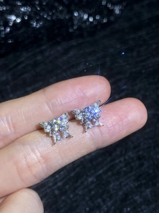 Close-up of S925 silver butterfly stud earrings with sparkling moissanite on fingertips