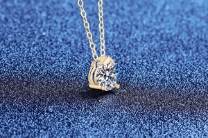 Macro shot of pear-cut moissanite pendant with gold three-prong setting and fine chain