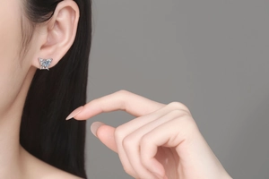 Detail of butterfly stud earring featuring a blue stone and shell pearl on ear