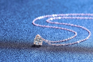 Macro view of brilliant round moissanite pendant with rose gold three-prong setting