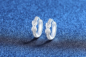 Gros plan de boucles d'oreilles créoles infini en argent et moissanite sur fond bleu