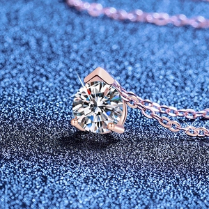 Sparkling round Moissanite pendant necklace with rose gold claw setting on a dark background