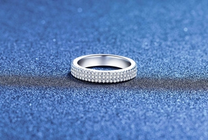 Close-up of triple-row moissanite Cuban eternity ring on blue glitter background