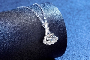 Macro detail of skirt-shaped pendant with 1ct moissanite on blue display stand