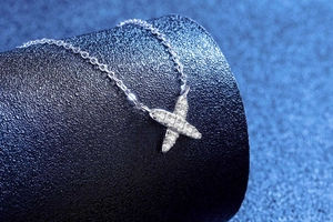 Macro shot of silver X-shaped pendant with sparkling moissanite stones on a chain