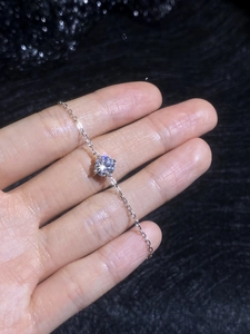 Detailed view of single round-cut moissanite stone in a four-prong silver setting