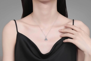 Close-up of fan-shaped pendant necklace with blue center stone and pave diamonds on model