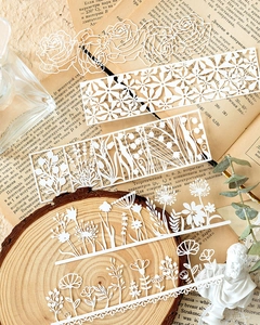 Dettaglio di cinque strisce di pizzo in carta bianca tagliate al laser per scrapbooking