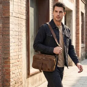 Brown crazy horse leather crossbody bag for men shown against a red brick wall