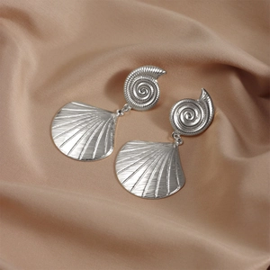 Detailed view of silver shell drop earrings with radial texture on champagne silk