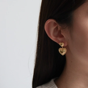 Boucles d'oreilles double cœur en or poli avec texture perlée vintage sur modèle