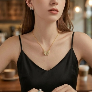 Elegant gold butterfly necklace with shimmering crystals on a model in warm indoor light
