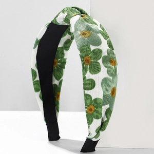 Green floral wide headband with cross knot design on a minimalist white background