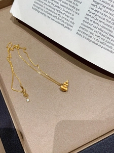 Macro shot of brushed gold pumpkin gourd pendant with pavé crystals on a silk chain