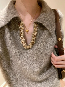 Macro shot of gold pumpkin gourd pendant on necklace styled with premium knitwear